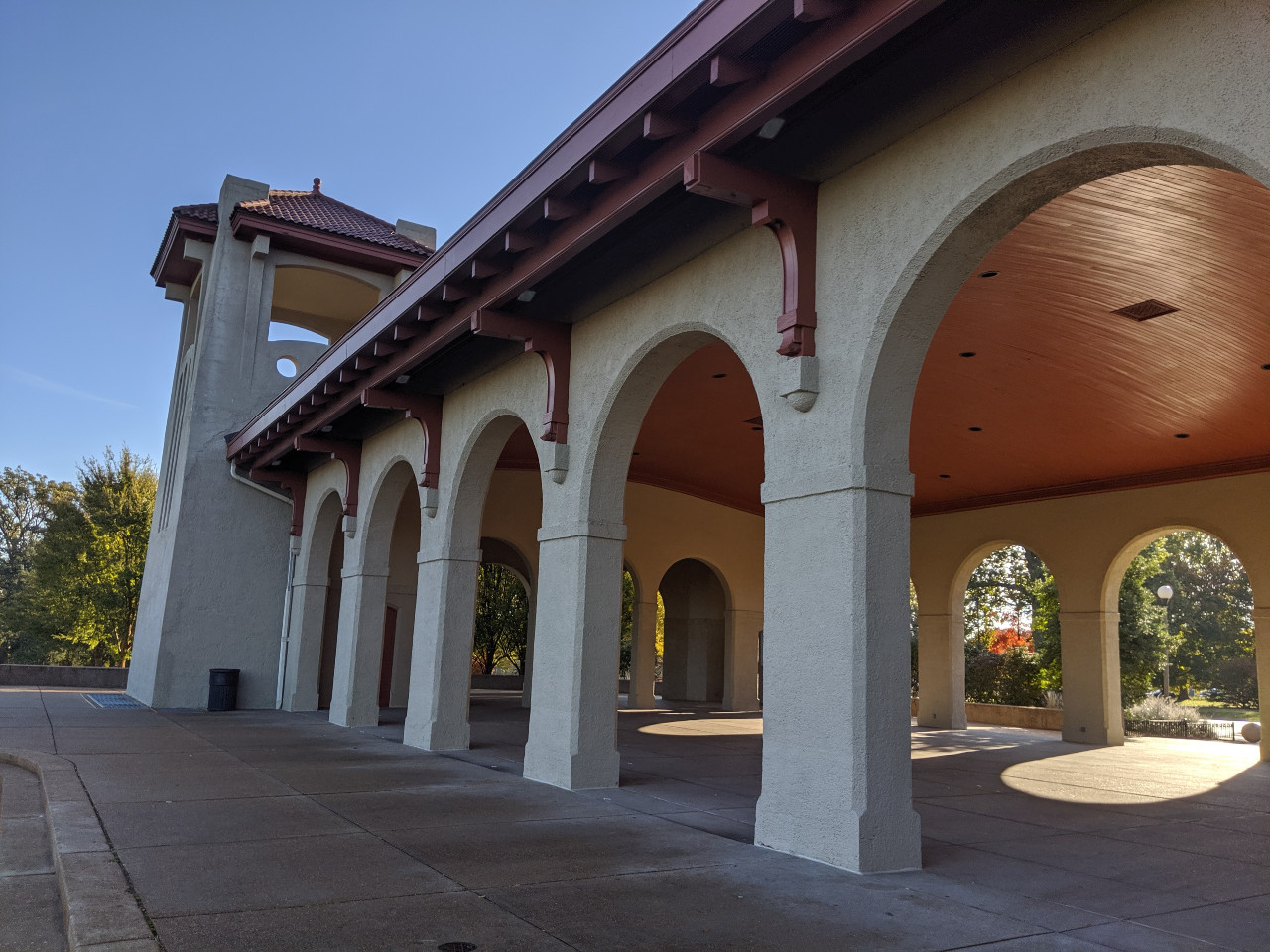 Sited on a high rise overlooking a fountain, the Mission Revival building has an open arcade on front and back facades, between highly ornamental towers. 
